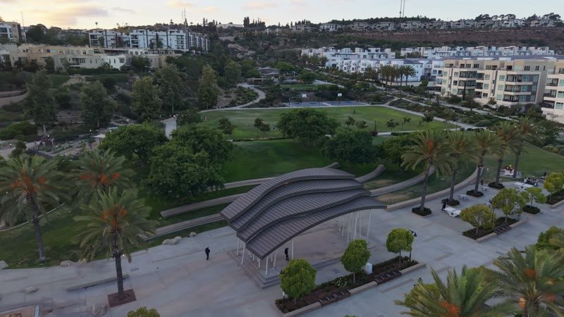 Civita Park Curved Steel Amphitheater Pavilion Above the Green – Wide Establishing Frame