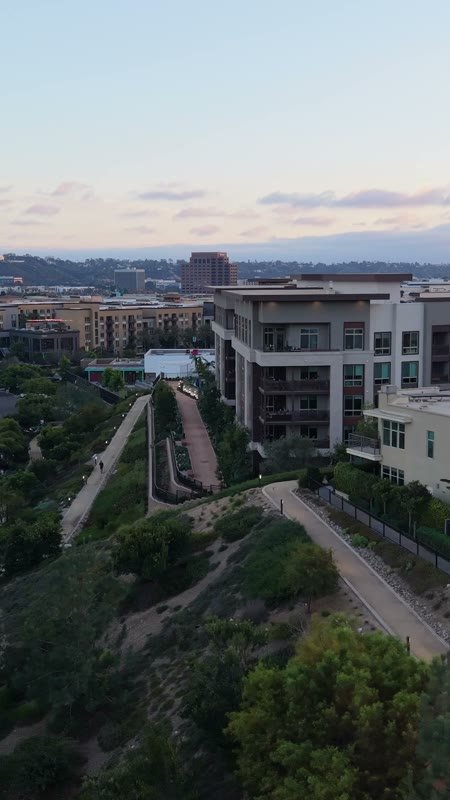 Civita Hilltop Residences Above the Community Garden Terraces at Dusk – Aerial View (Vertical)