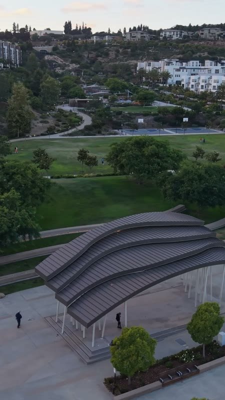 Civita Park Curved Steel Amphitheater Pavilion Above the Green – Wide Establishing Frame (Vertical)