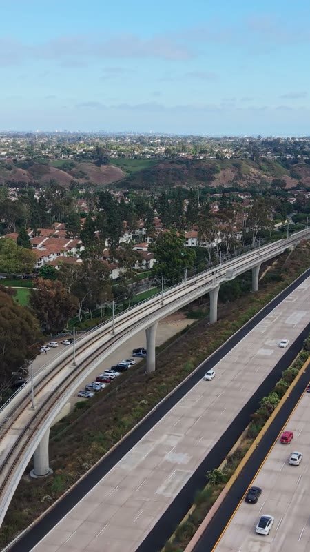 Elevated Trolley Guideway Curving Above the I-5 in University City – Wide Establishing Frame (Vertical)